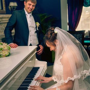 жених слушает игру невесты на рояле - профессиональная съемка свадьбы